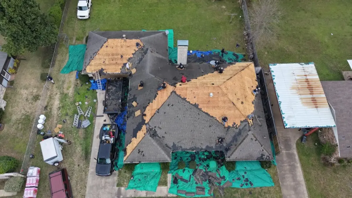 Bohon crew tearing off and re-decking a roof, with tarps protecting the yard